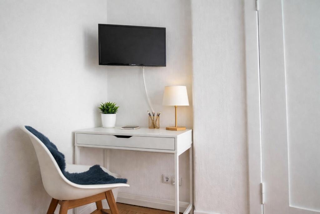 a white desk with a chair and a tv on a wall at Haus Wilbrand Ferienzimmer 1 in Warnemünde