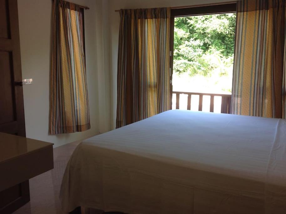 sypialnia z dużym łóżkiem i oknem w obiekcie Ban sabai woktum w mieście Thongsala