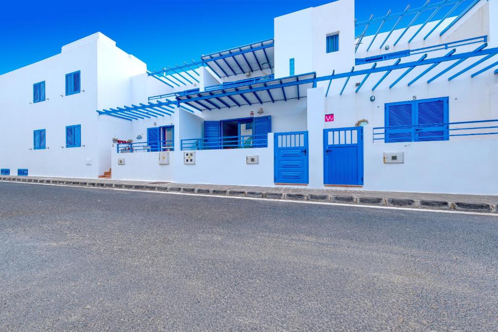 a white building with blue doors on a street at Casa Eva in Famara