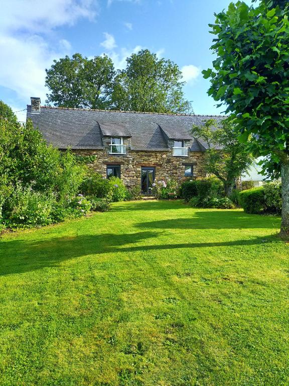 a stone house with a large lawn in front of it at la guichardaye in Tréal