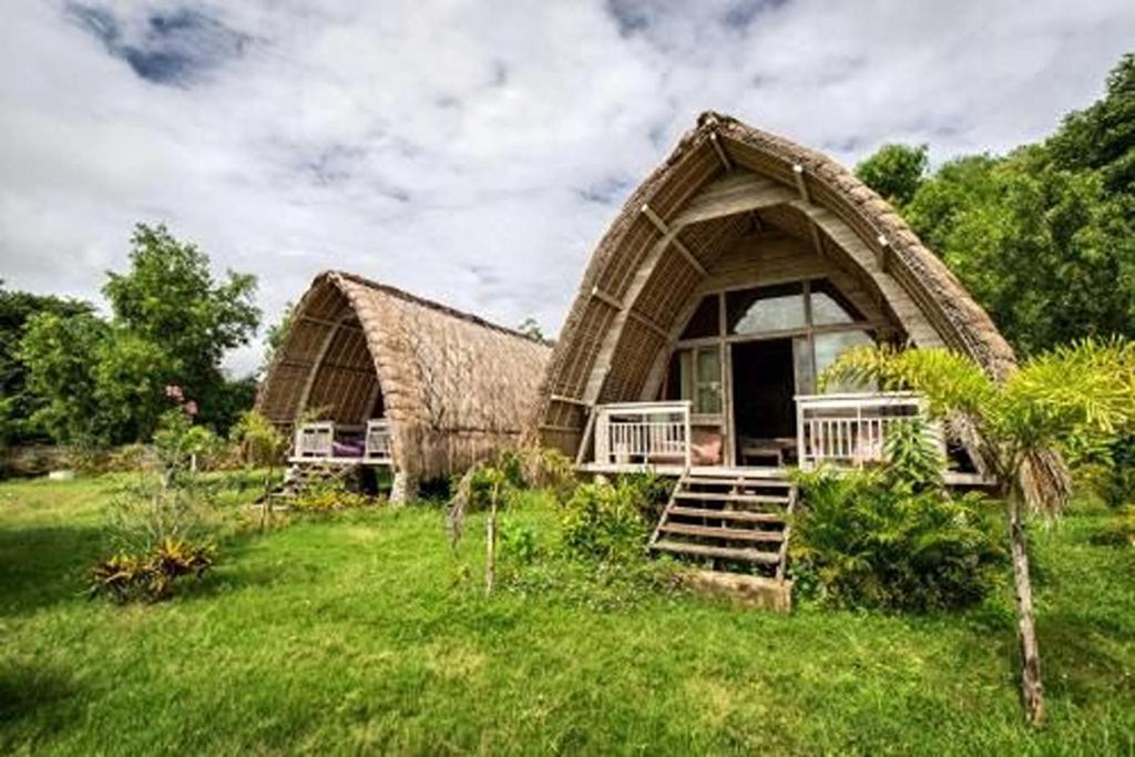 a house with a thatched roof in a field at Gipsy Beach Bungalows in Sekotong