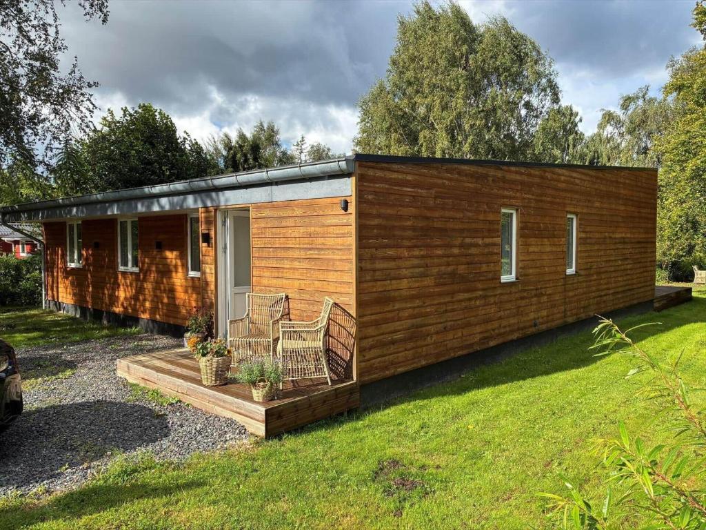 a tiny house with a deck in a yard at FJ1202-Jaegerspris-Lille-Engvej-7 in Jægerspris
