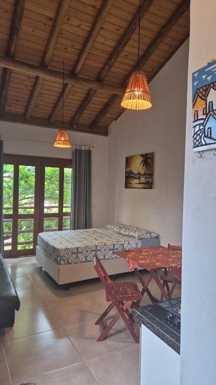a bedroom with a bed and a table and chairs at Recanto das Amendoeiras in Guarda do Embaú