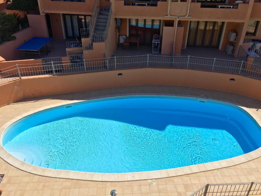 a large blue swimming pool in front of a building at La Spiga Apartments in Castelsardo