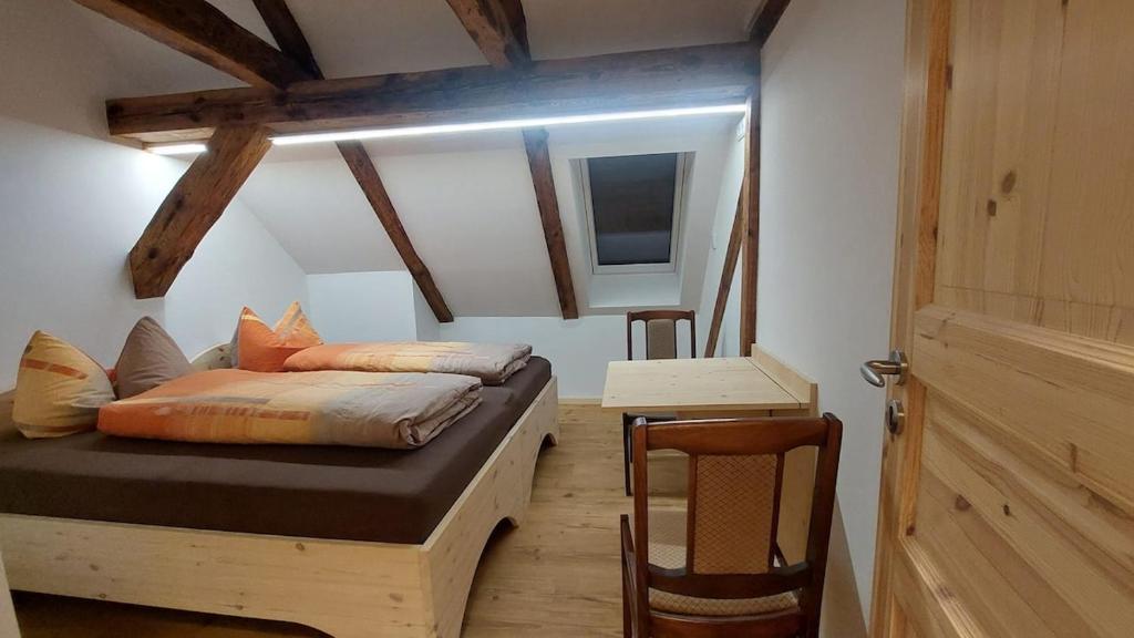 ein Schlafzimmer mit einem Bett, einem Tisch und einer Tür in der Unterkunft Oderlandblick Apartment in Friedersdorf
