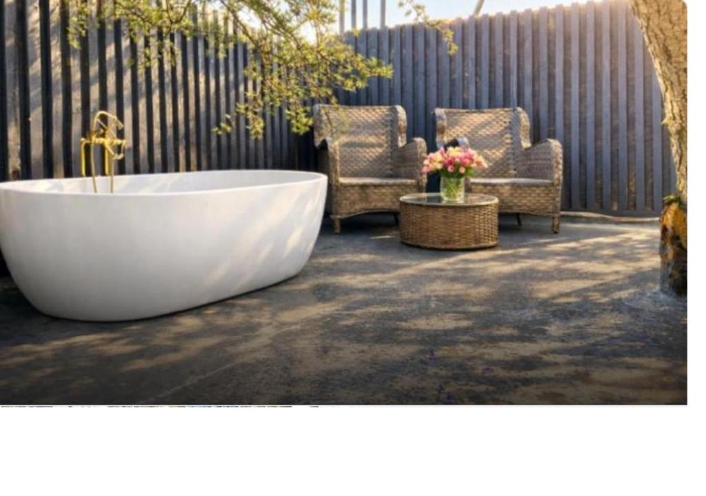 a bath tub sitting on a patio with two chairs at The Orchard's Nook Treehouse in Cottenham