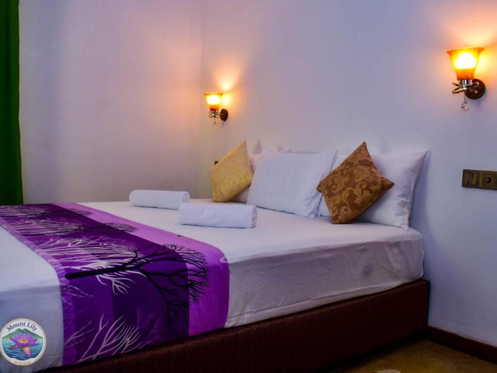 a bed in a room with two lights on the wall at Mount Lily Mirissa in Mirissa