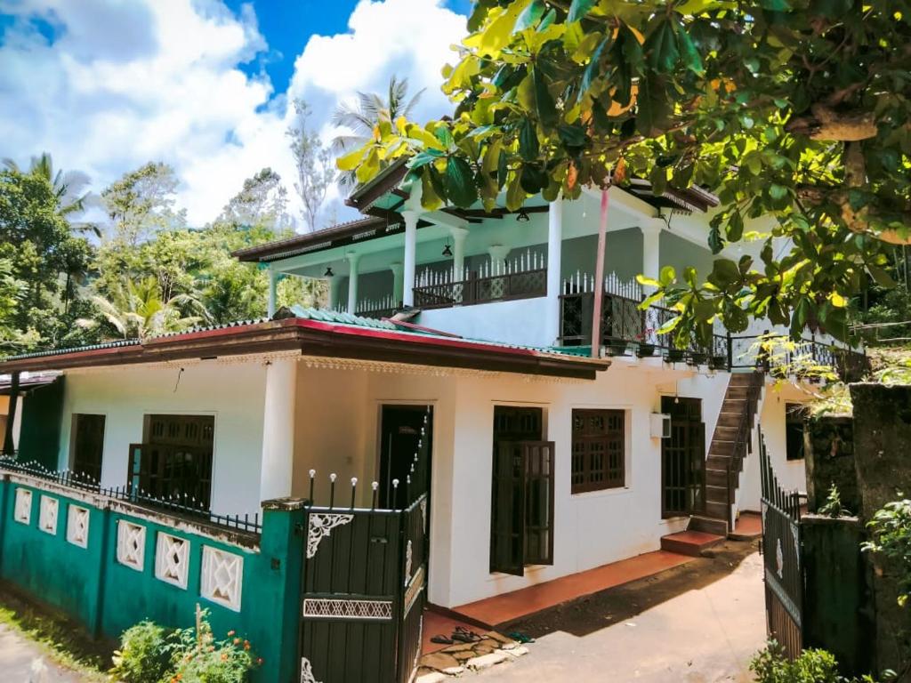 a house with a green fence in front of it at Wellassa Hillside Villa in Kendagolla