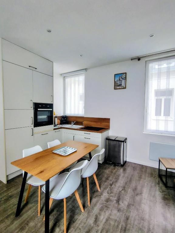 a kitchen with a wooden table and some chairs at escapade à Wimereux in Wimereux