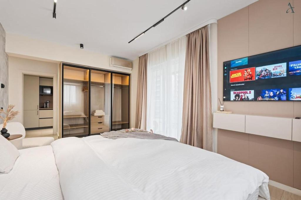 a bedroom with a white bed and a flat screen tv at Studio in Dimri Residence in Bucharest