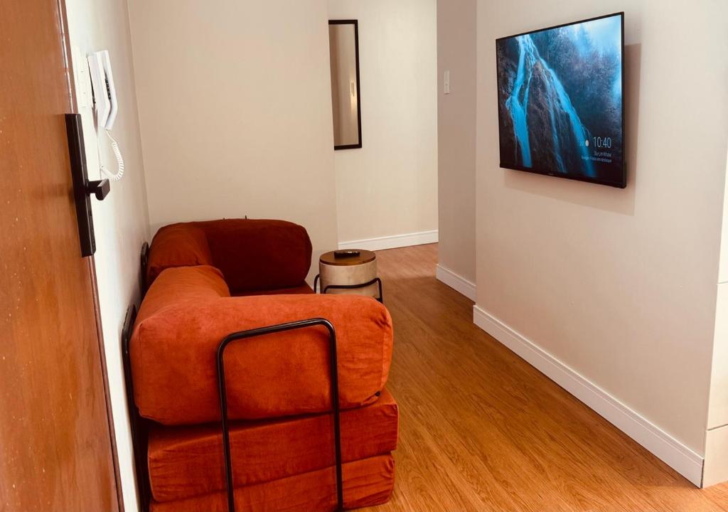 a living room with a chair and a tv on a wall at Apartamento com ar condicionado e lava e seca in Cascavel