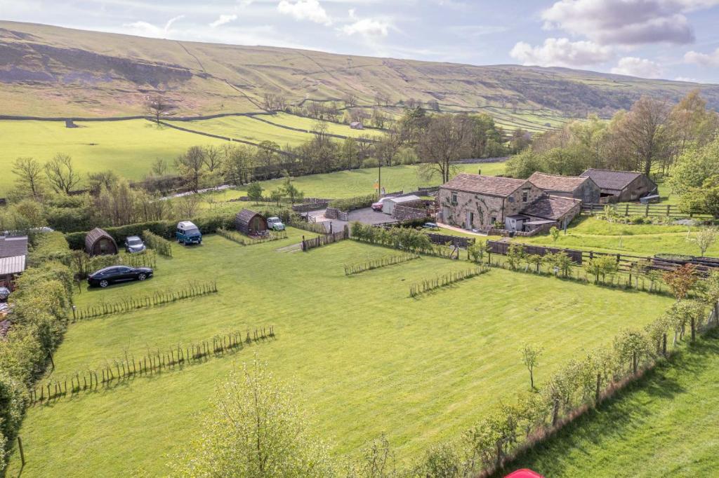 an aerial view of a large green field with a house at Wharfe Camp Glamping in Kettlewell