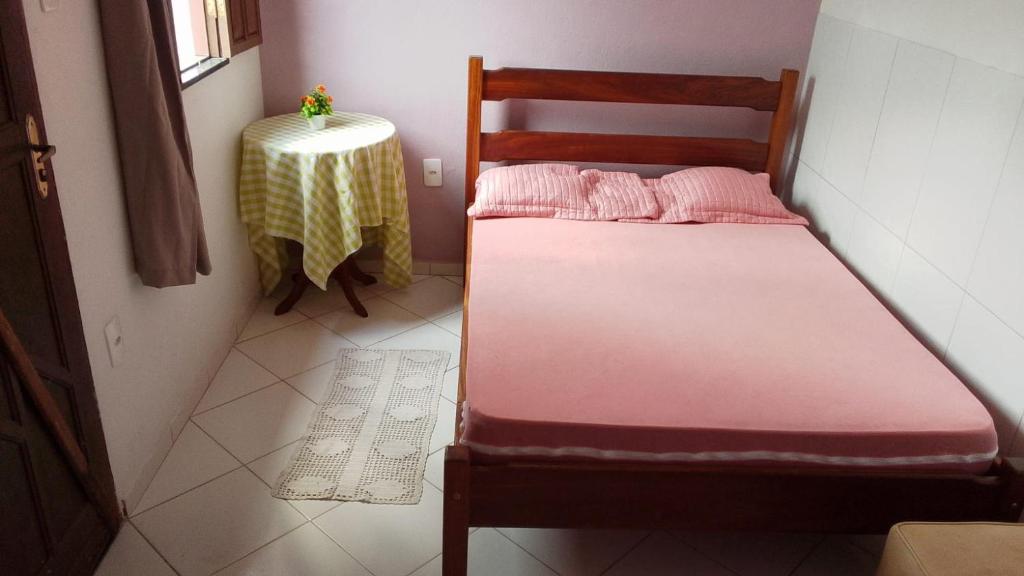 a small bed in a small room with a table at Casa Rosa da Ilha - Suíte Confortável com Ventilador e Jardim in Vera Cruz de Itaparica