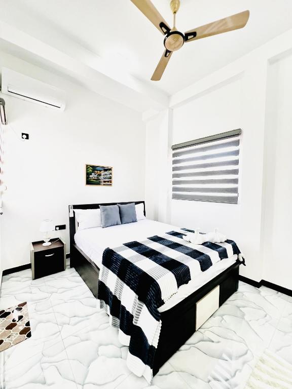 a bedroom with a black and white bed and a ceiling fan at Rehan Sunset Villa in Negombo