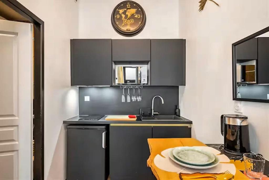 a kitchen with black cabinets and a sink and a table at Romantic getaway with Balneo Centre Lorient in Lorient