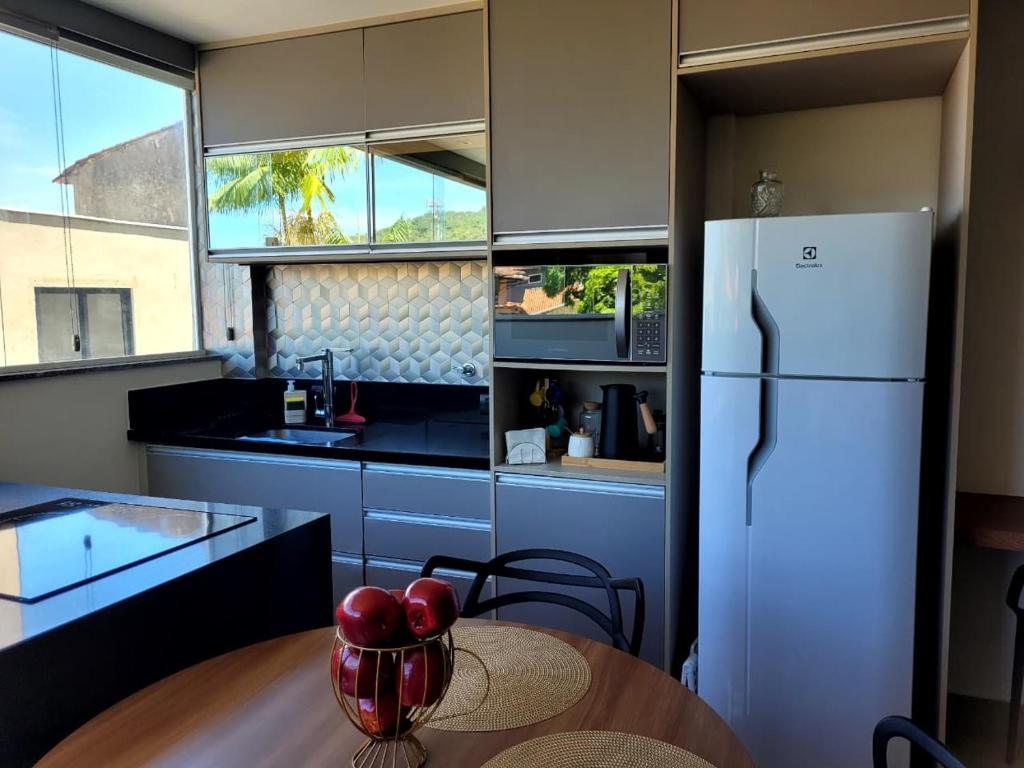 a kitchen with a table and a white refrigerator at Flat Praia Itacoatiara in Niterói