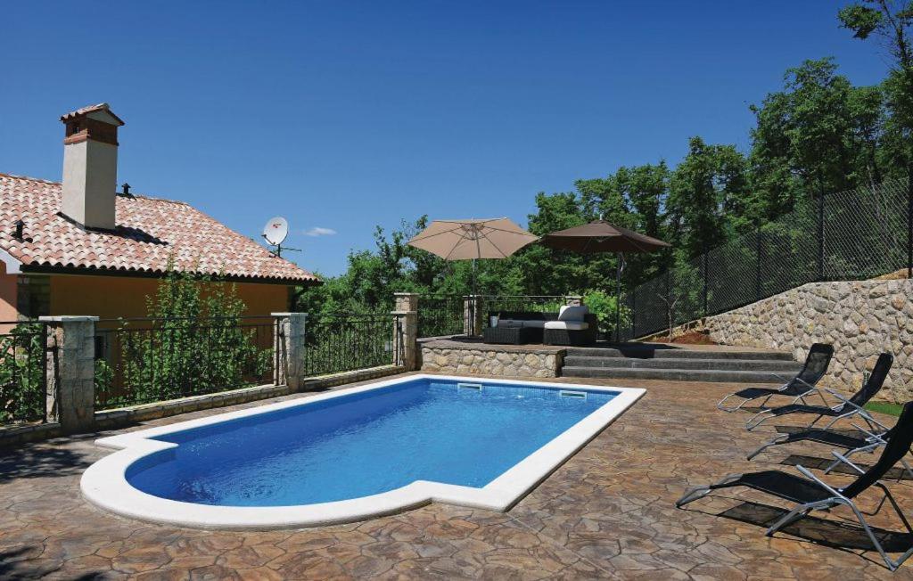 a swimming pool in a yard with chairs and an umbrella at Villa Nina Labin-The oasis of peace in Labin