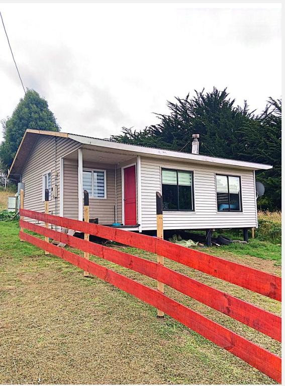 a house with a red fence in front of it at Cabañas "Parada Tentelhué" in Rolecha