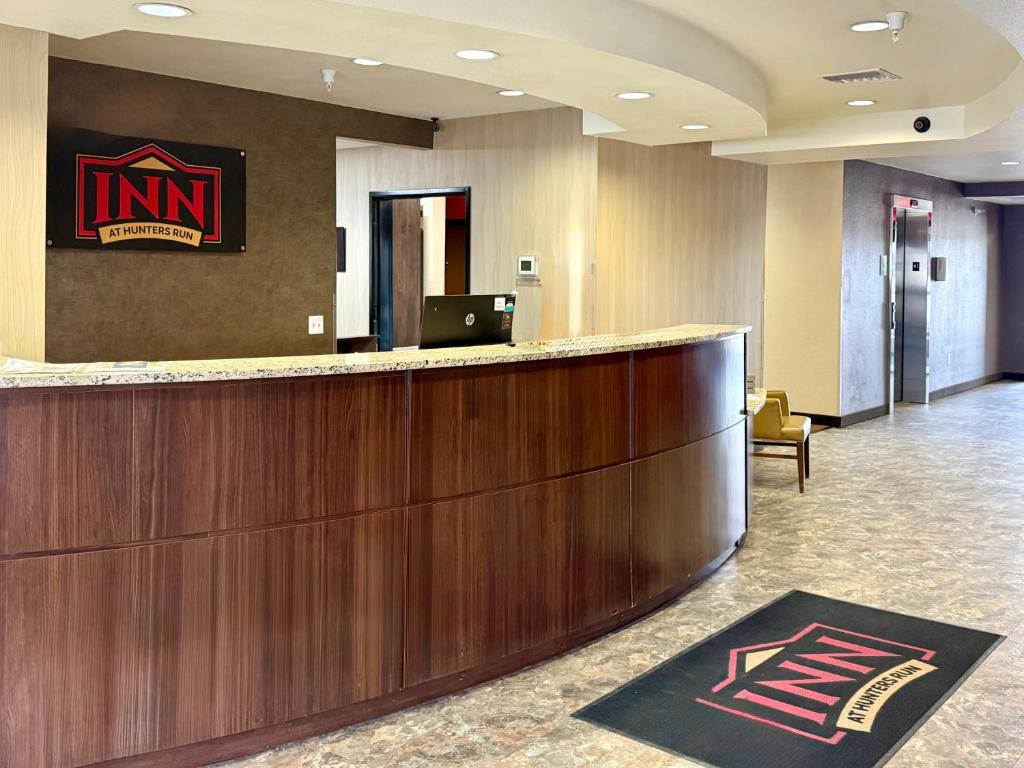 a hotel lobby with a bar with a sign on the wall at Inn at Hunters Run in Watford City