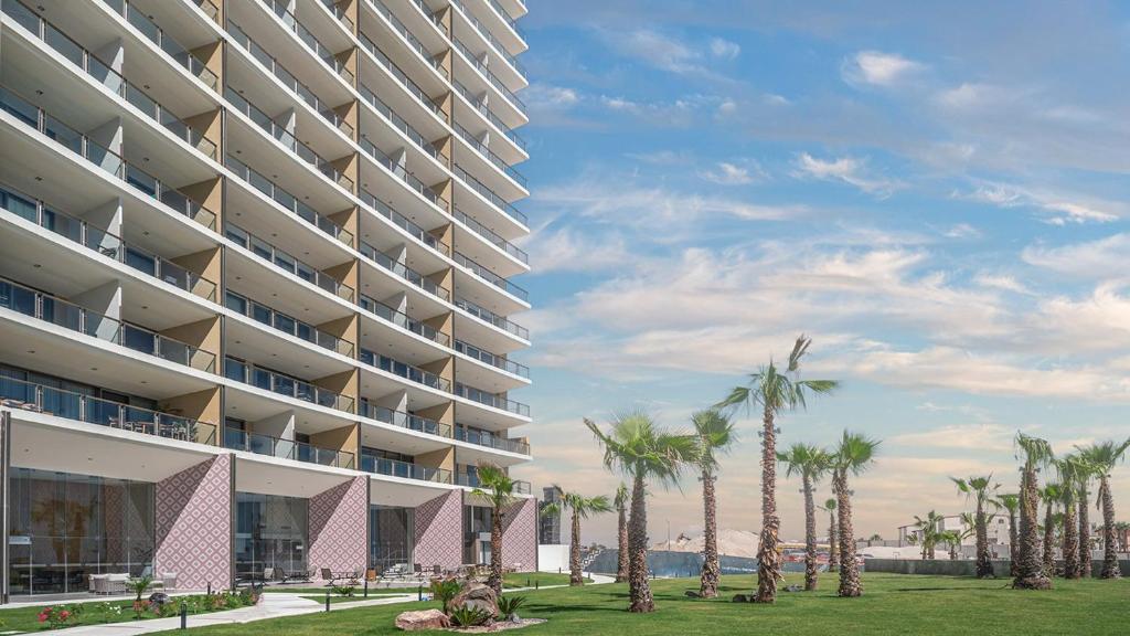 a rendering of a large apartment building with palm trees at Elegant Beachfront Getaway with Unmatched Views in Puerto Peñasco