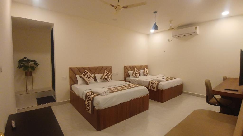 a room with two beds and a table and a desk at Hotel Venus in Jabalpur