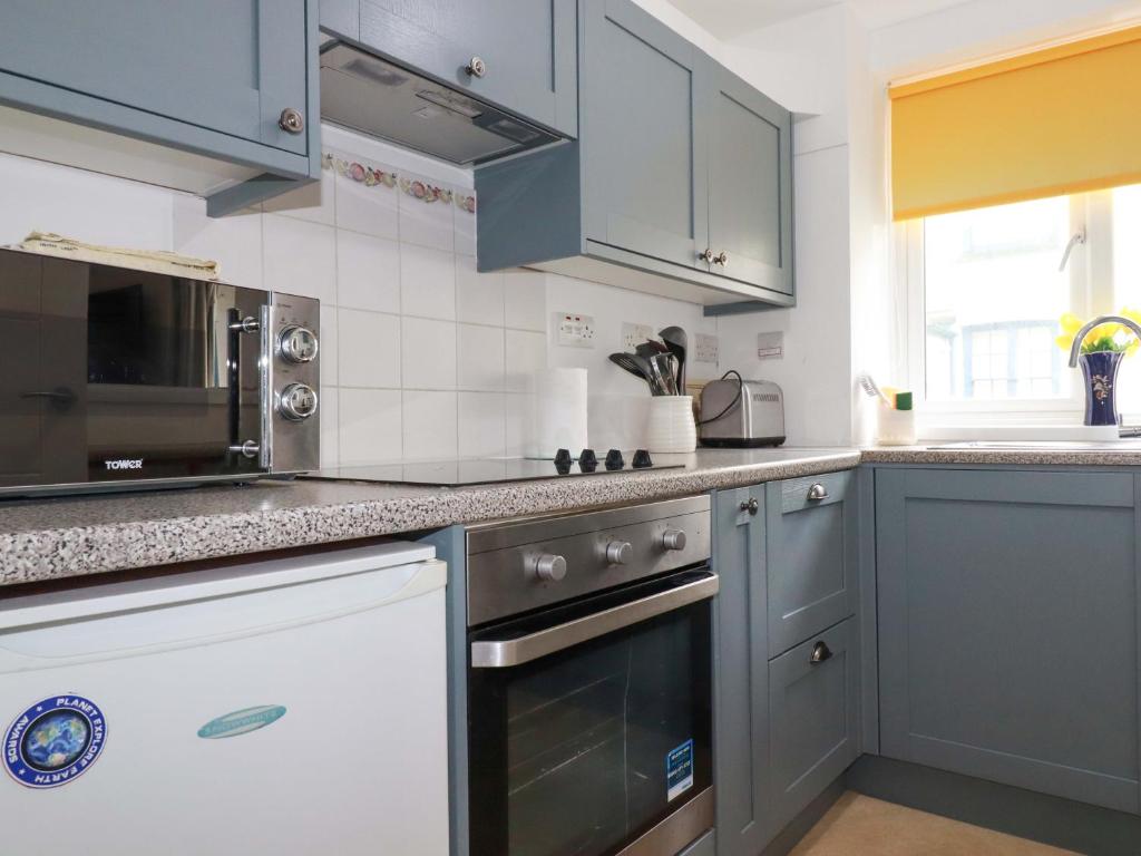 a kitchen with blue cabinets and a stove top oven at Seaside Apartment in Looe