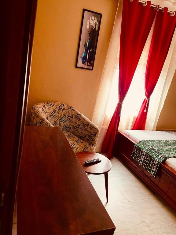 a bedroom with a bed and a chair and a window at Binyuma Suites Motel in Kampala