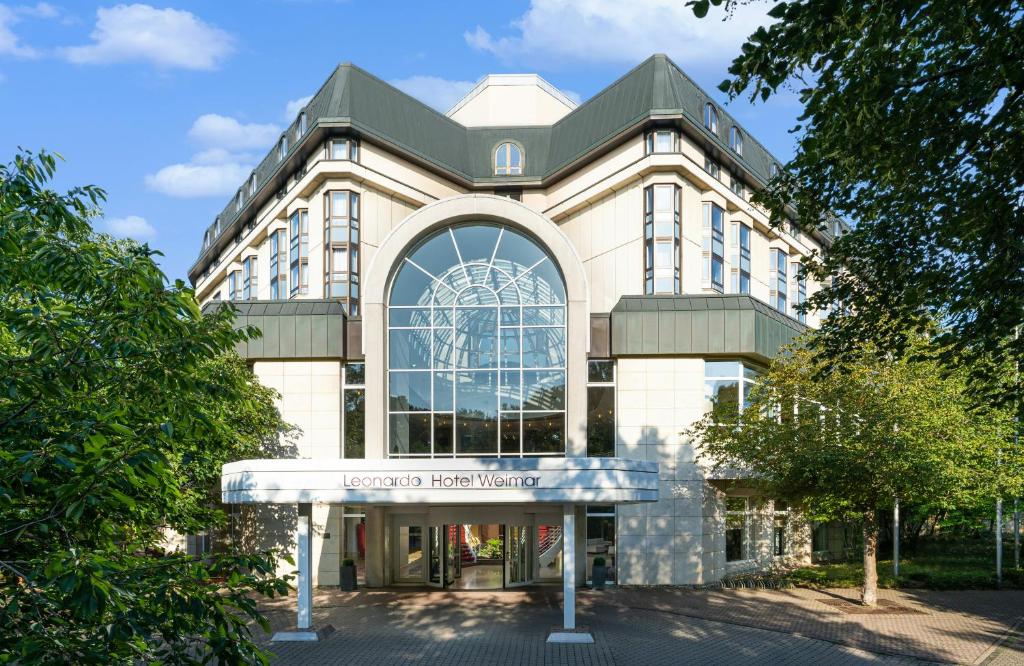 a building with a large window on the front of it at Leonardo Hotel Weimar in Weimar