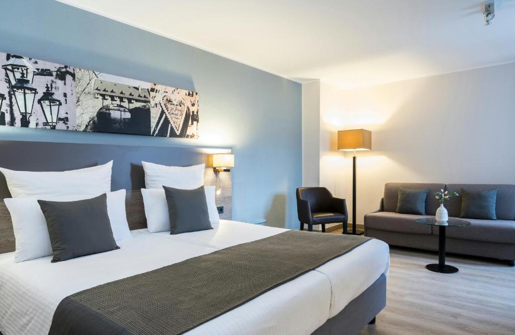 a hotel room with a bed and a couch at Leonardo Hotel Nürnberg in Nuremberg