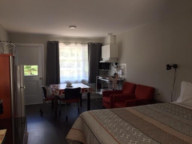 a bedroom with a bed and a table and a couch at Motel Domaine Expédition in Labelle