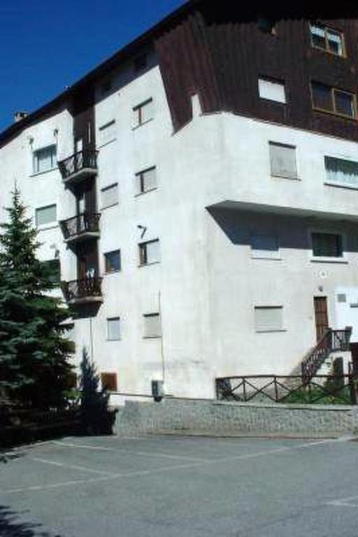 a large white building with a tree in front of it at Apartment 'Il Capriolo by Interhome in Sauze d'Oulx