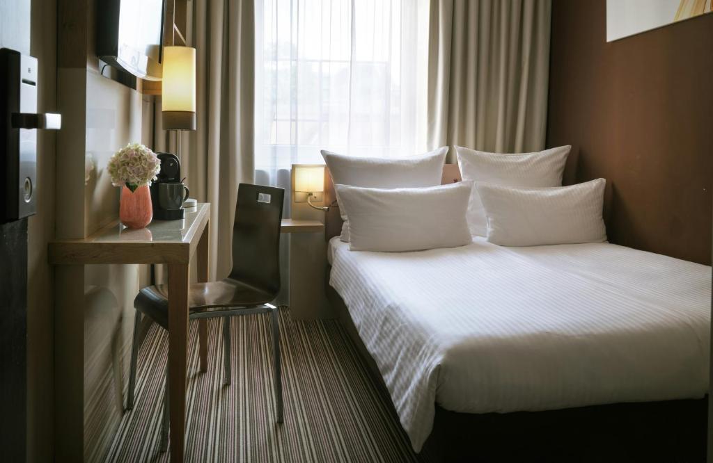 a hotel room with a bed and a table and a window at Leonardo Boutique Hotel Munich in Munich