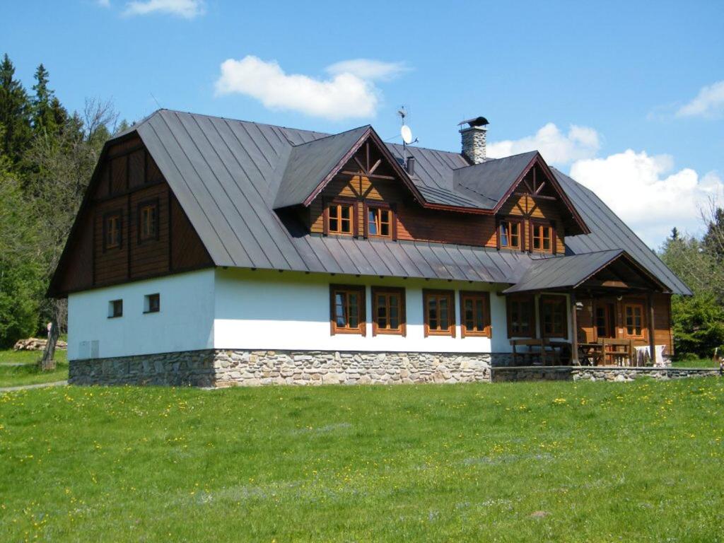 a house with a gambrel roof on a green field at Chalupa u Smrčiny in Janske Lazne