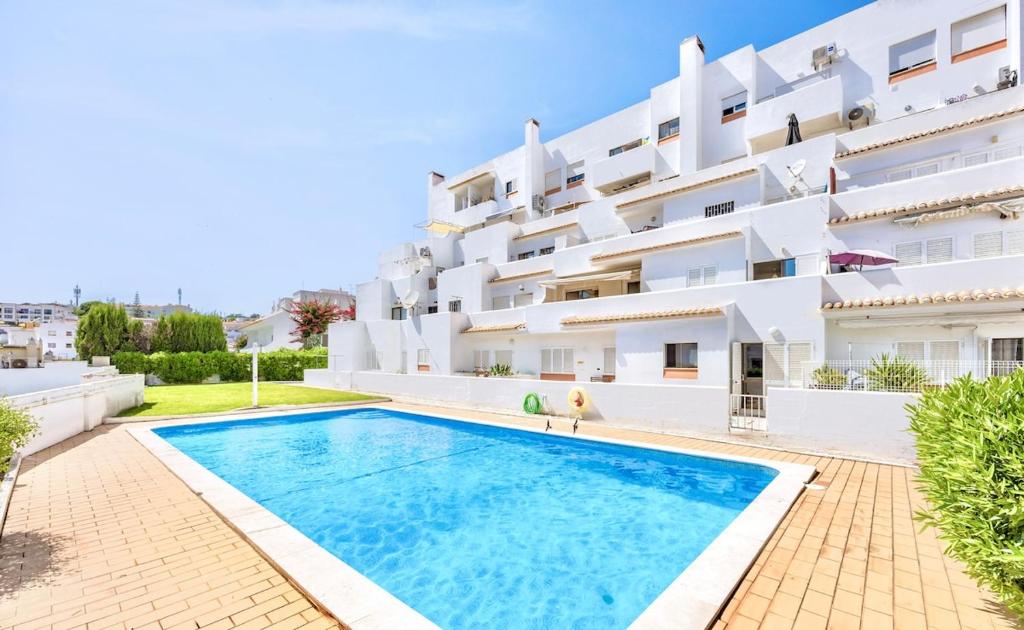 a villa with a swimming pool in front of a building at Albufeira City Centre Apartment with Pool in Albufeira