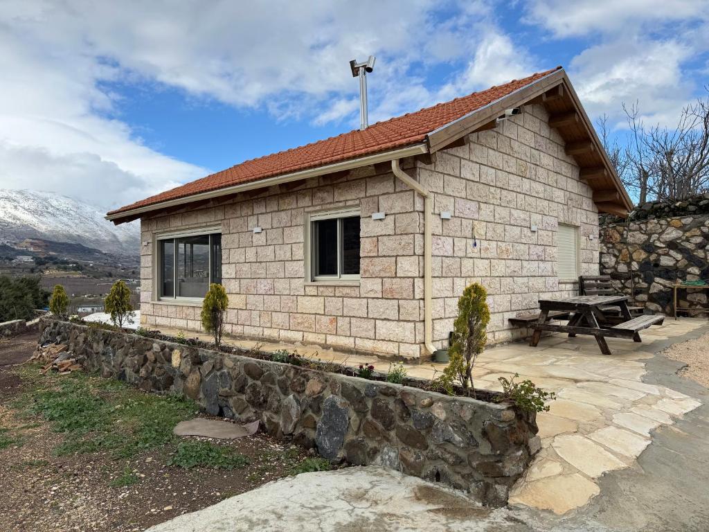 a small house with a stone wall and a picnic table at צימר בטבע in Majdal Shams