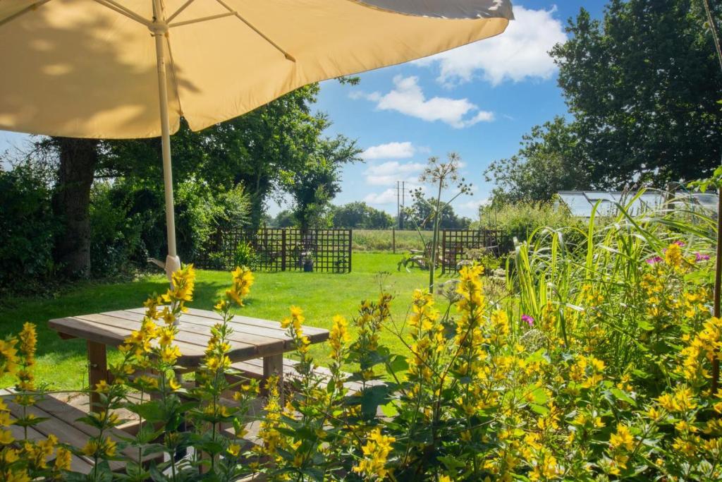 a picnic table with an umbrella in a garden at 2 Bed in Bodham oc-2082 in Bodham