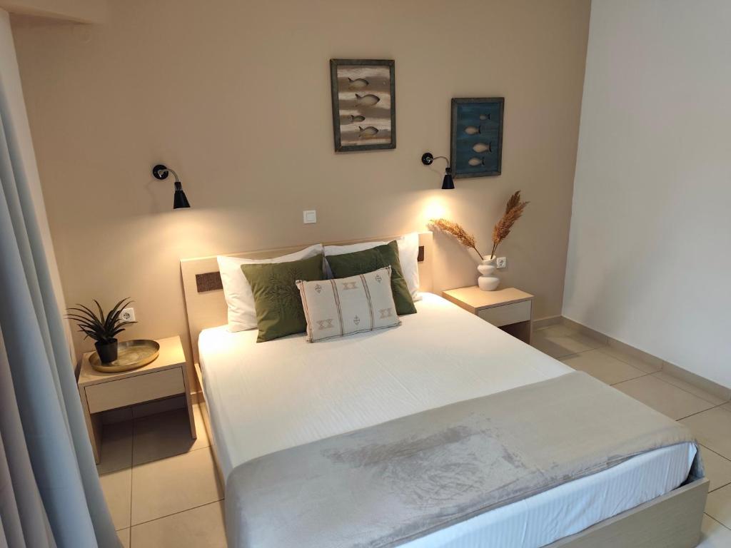 a bedroom with a large white bed with two tables at ILIDA apartments in Nea Peramos