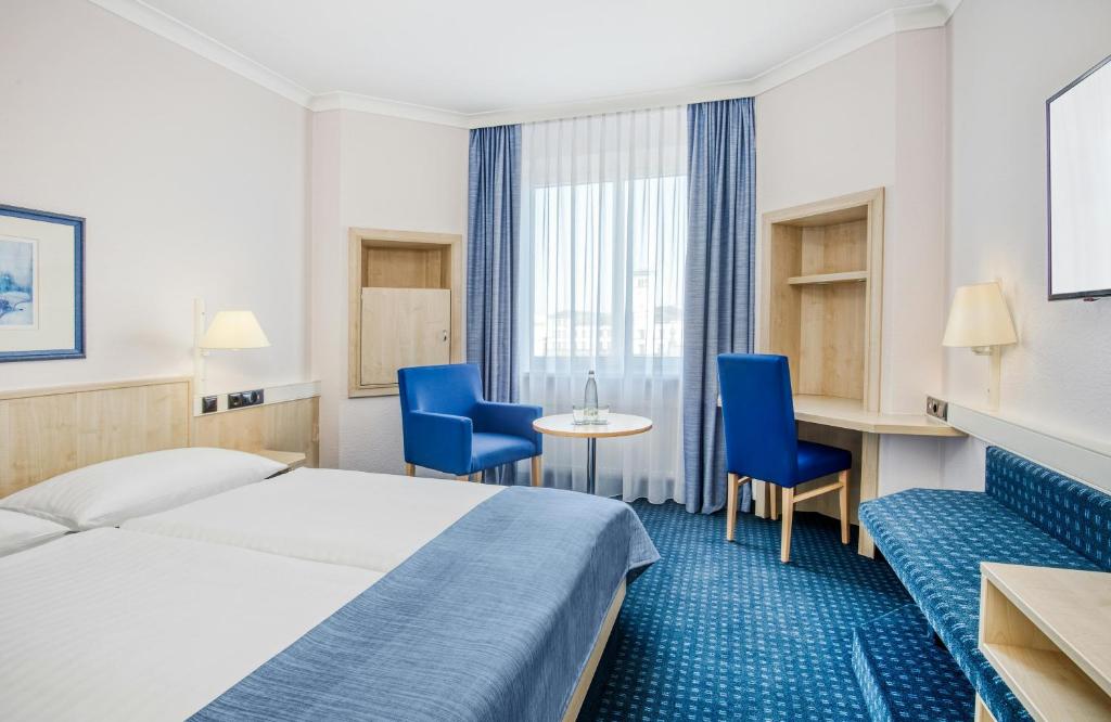 a hotel room with a bed and chairs and a table at Hotel Erfurt City Center by Leonardo Hotels in Erfurt