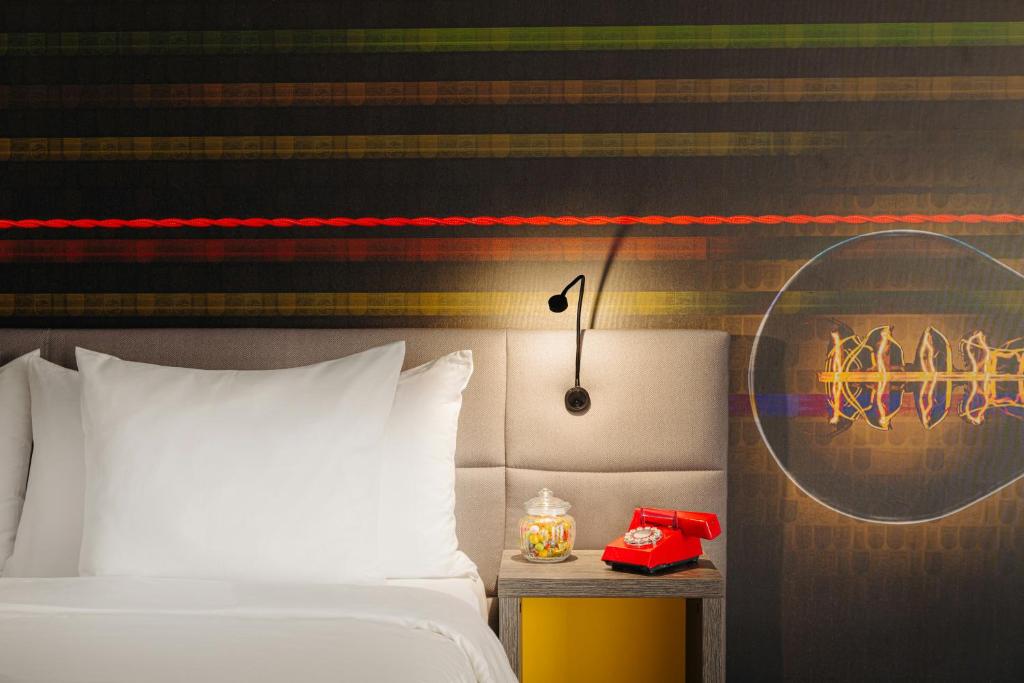 a bedroom with a bed and a red phone on a table at Leonardo Hotel Eindhoven City Center in Eindhoven