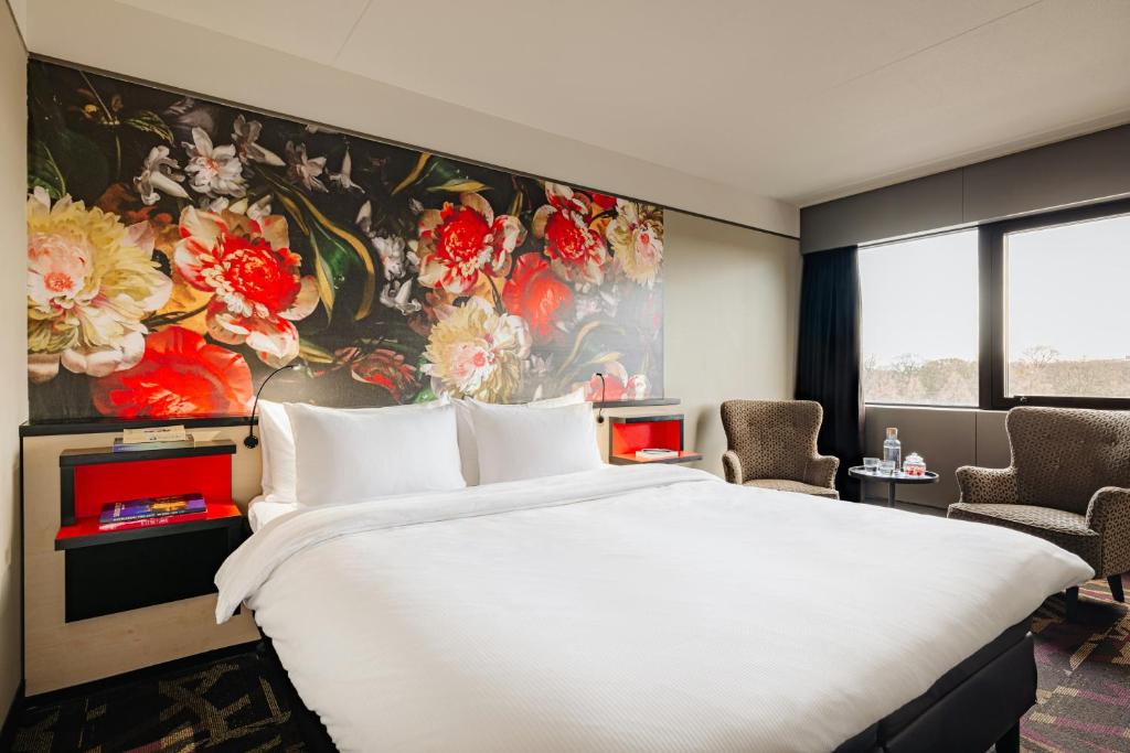 a bedroom with a large white bed and a painting at Leonardo Hotel Den Haag Babylon in The Hague
