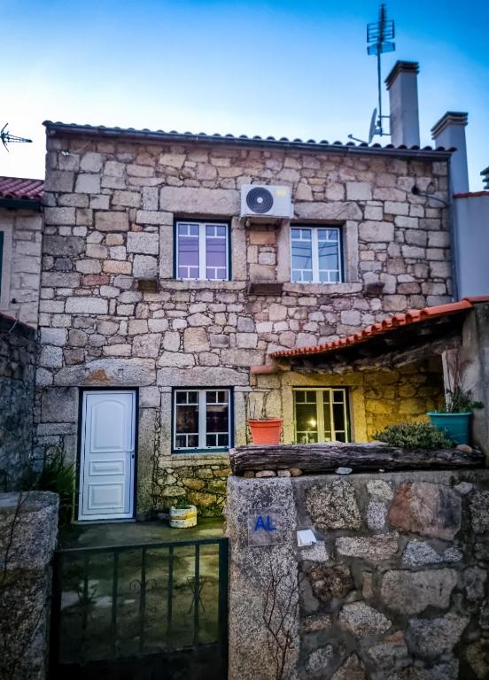 a stone house with a white door and windows at Casa Martins by Tear in Aldeia de João Pires