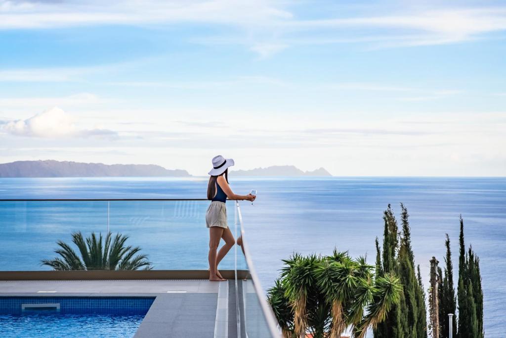 a woman standing on a balcony looking at the ocean at Half Gate Villa - Ocean View & Private Pool in Gaula