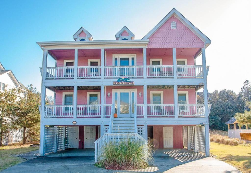 a large pink house with a large balcony at Raspberry Duck - Duck Landing, 525 Yds to Beach, Pool, Tiki Bar, Hot Tub, Close to Downtown in Duck