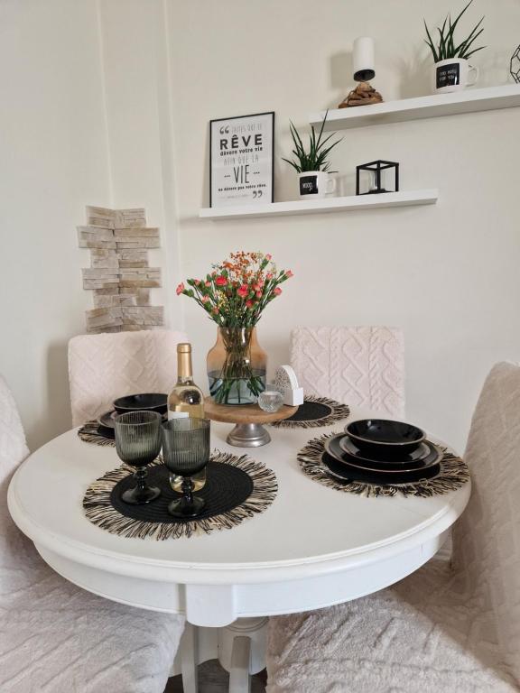 a white table with a bottle of wine and flowers on it at PIK-KWATERY in Olsztyn