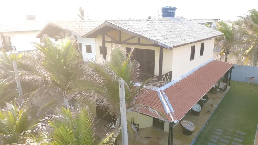 a white house with palm trees in front of it at Nascimento BEACH in Águas Belas