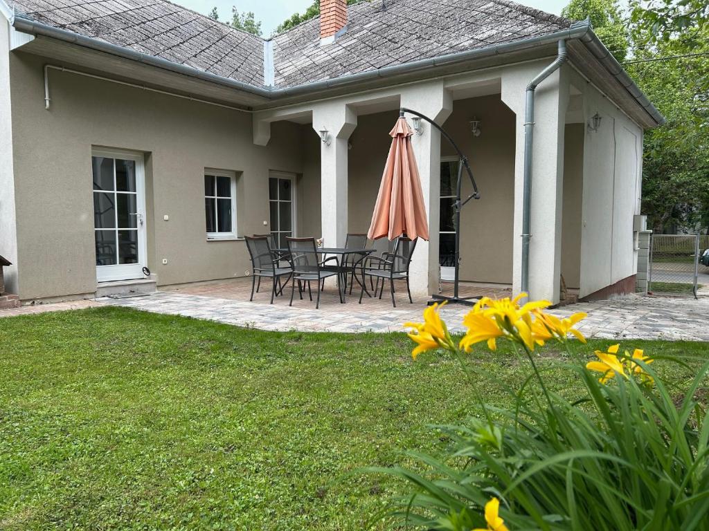 a house with a patio with an umbrella and chairs at Giulia Vendégház in Balatonboglár