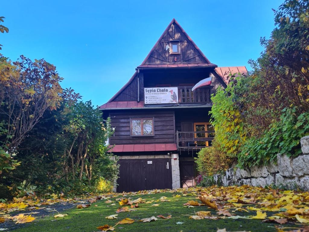 a wooden house with a yard with leaves on the grass at Sępia Chata dom do wynajęcia in Świeradów-Zdrój
