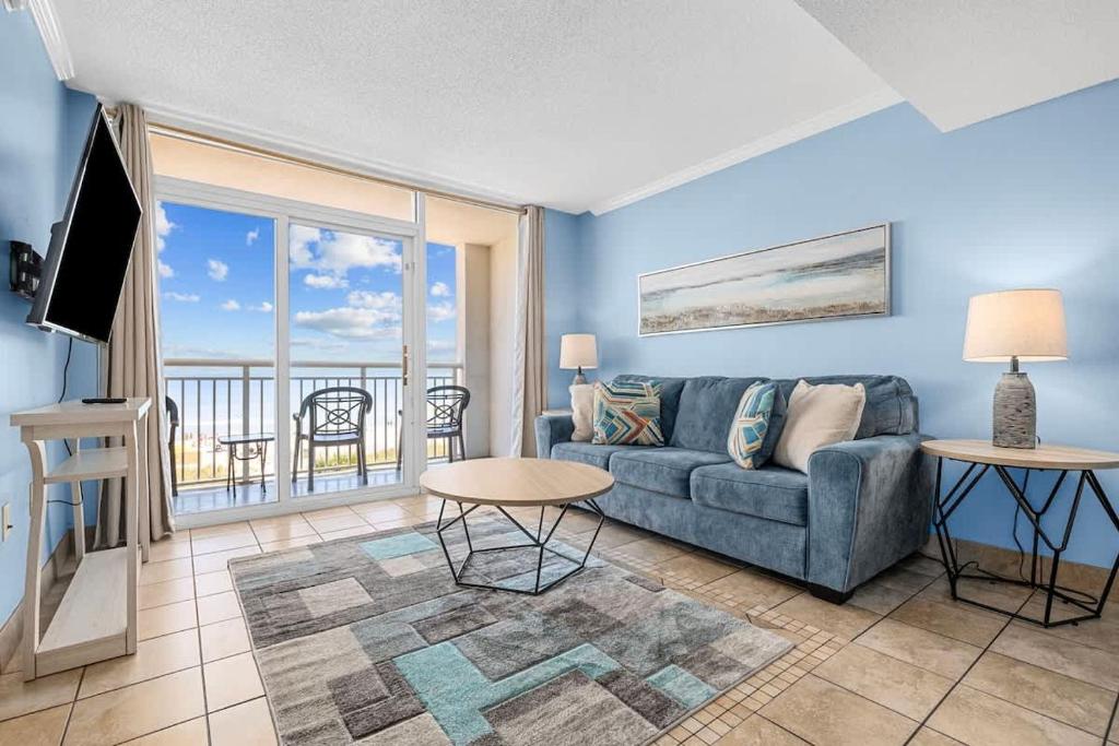 a living room with a couch and a balcony at Camelot by the Sea Oceanfront 2BR in Myrtle Beach