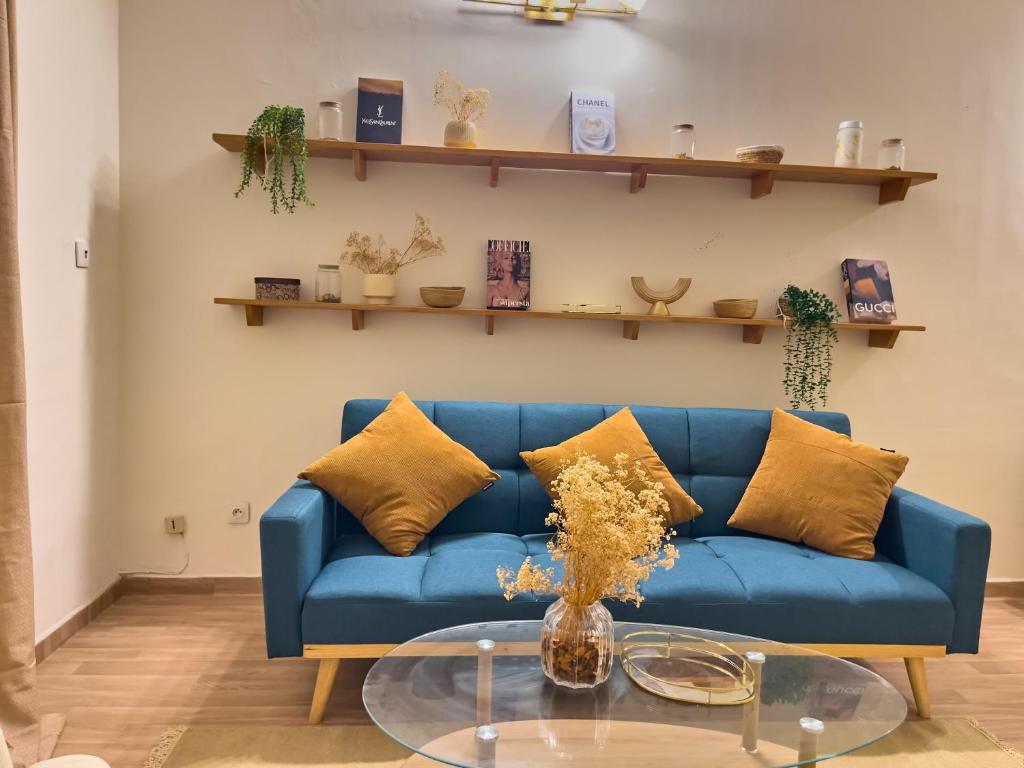 a blue couch in a living room with a glass table at Bohemian & White Getaway Zone4 in Abidjan