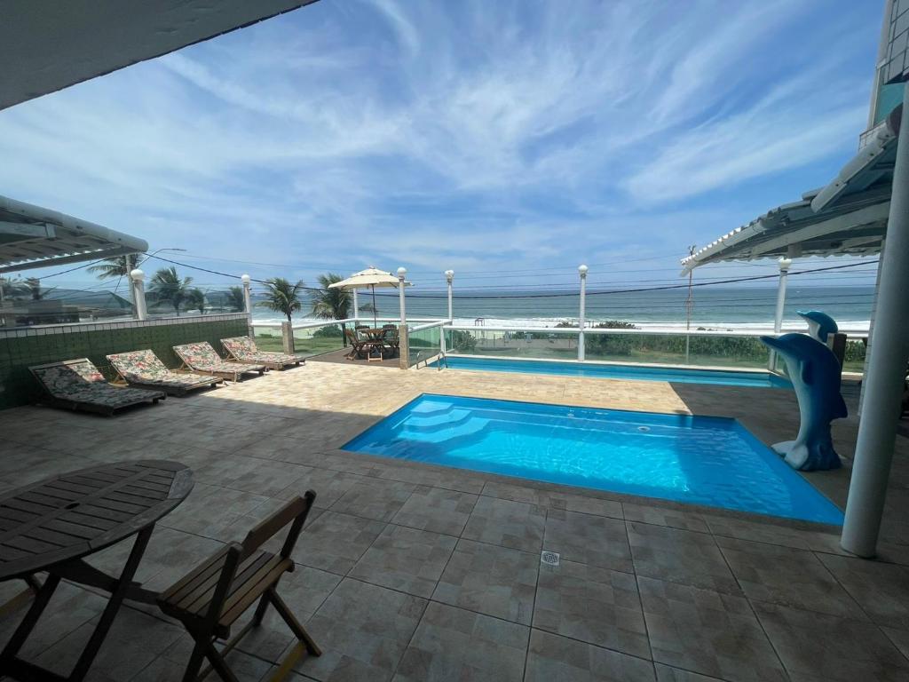 a swimming pool with a view of the ocean at Hotel Aconchego da Vila A in Saquarema